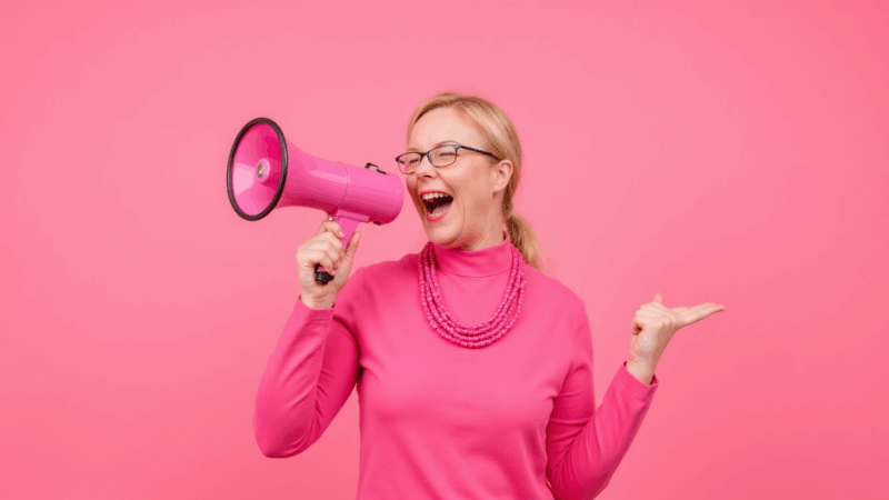 Claudia mit pinkem Megafon vor pinkem Hintergrund.