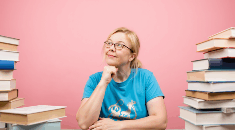 Claudia sitzt zwischen zwei Bücherstapeln.